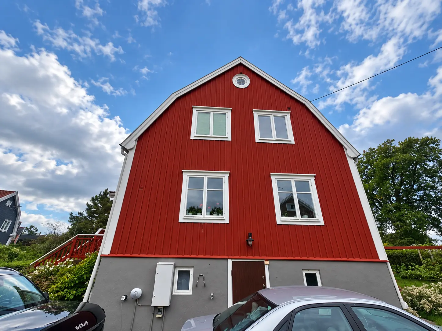 Fastighet med röd träpanel, vita foder och grå grund.