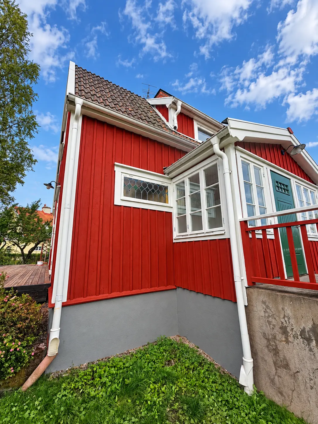 Rödmålad träfasad med vita foder och grå sockel i Västerås.